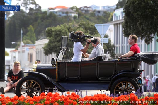 Man speaks to camera in moving vintage car on Marine Parade, Art Deco Weekend, Napier photograph